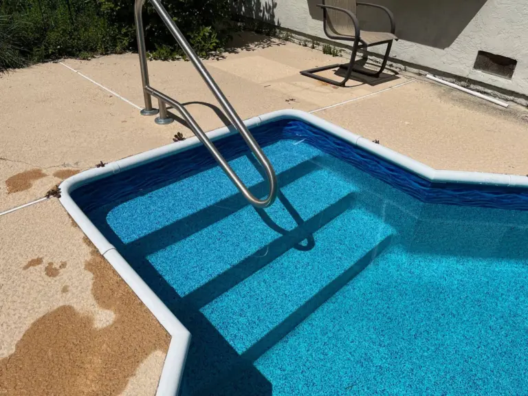 Vinyl-covered corner steps with a stainless handrail in a light blue pool