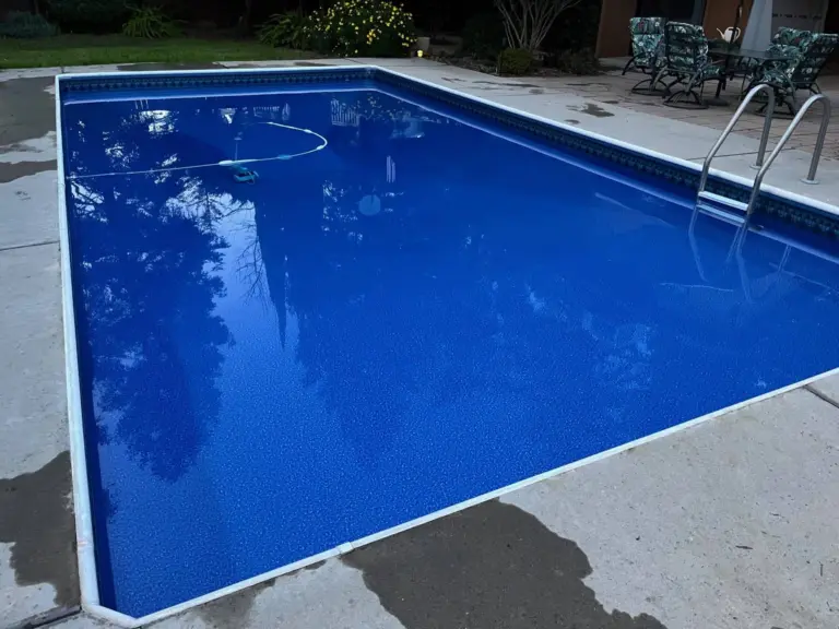 Rectangular pool with a dark blue liner, white coping and a stainless ladder