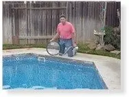 Covering the pool light before a leak test, a technician kneeling at the pool edge