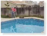 Sweeping the pool floor with the leak detector on a long pole