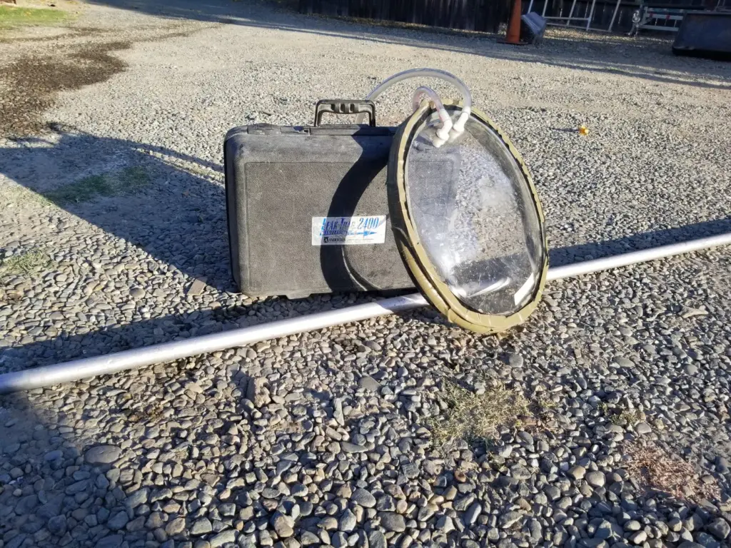 Leak detection gear on the driveway: the detector case and the clear dome that covers the pool light during a test