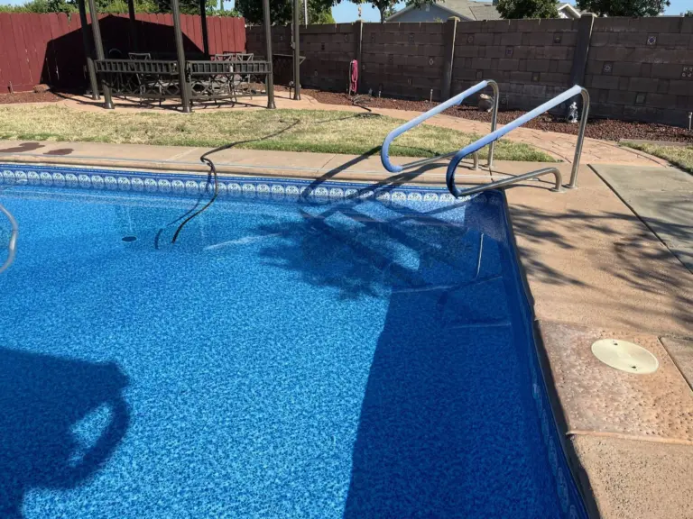 Light blue pool with a mosaic border band and a stainless ladder