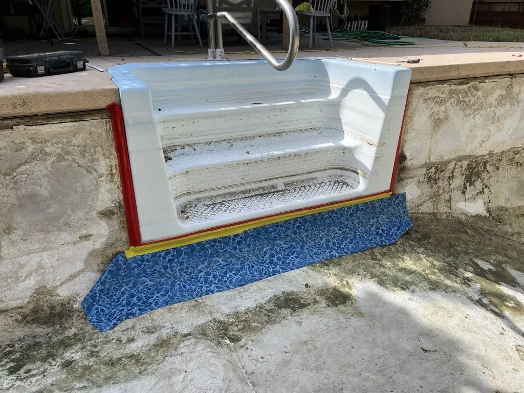 An old white fiberglass step set into the pool wall, before the new liner goes in