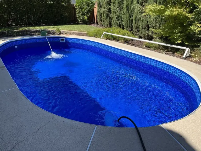 Oval pool with a deep blue liner, a return jet rippling the water