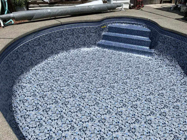 A new pebble-pattern liner in an empty kidney-shaped pool, steps at the shallow end