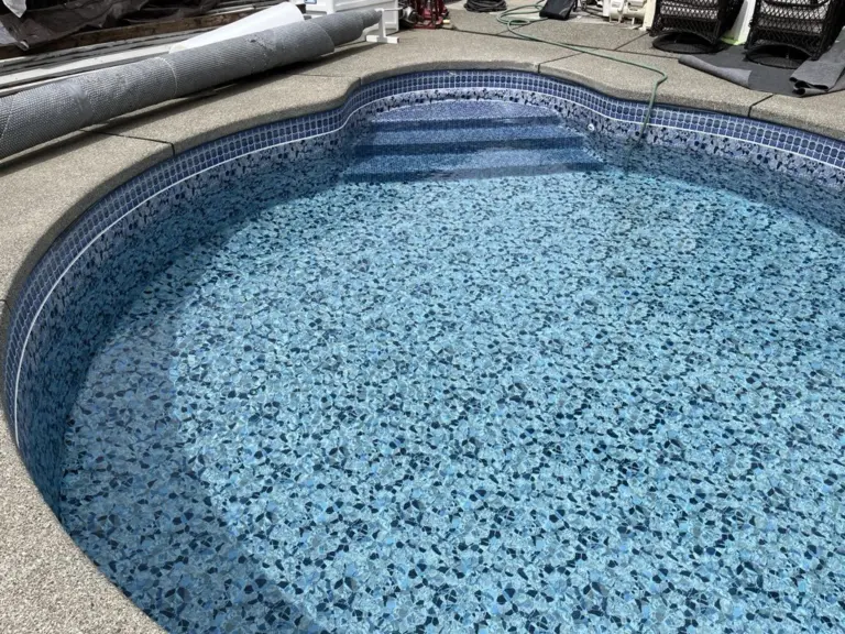 The same kidney-shaped pool partly filled, the pebble-pattern liner turning blue under water