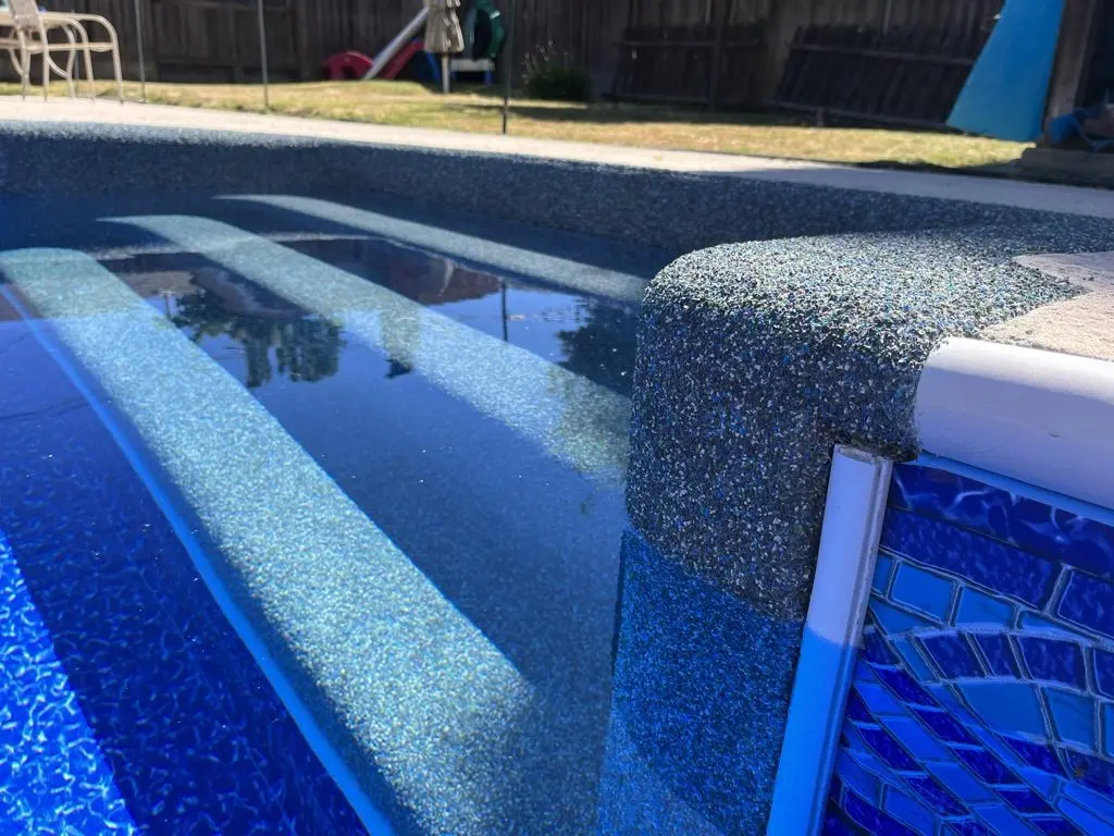 Rebound-coated bench and steps in a full pool, a mosaic tile border along the wall