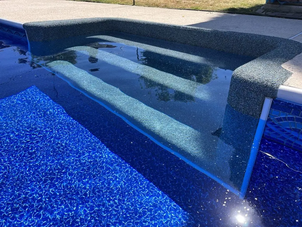 Rebound-coated bench seat running along the side of a pool with a blue liner