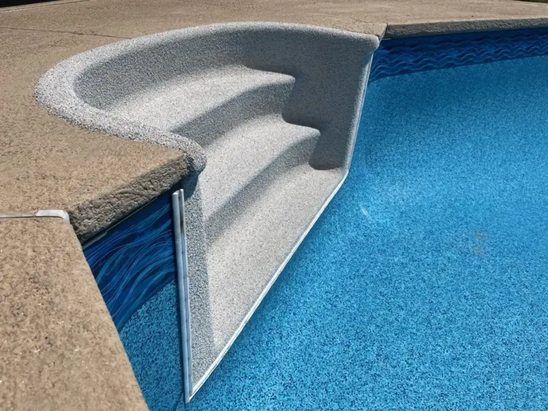 Gray Rebound steps at the corner of a pool with a light blue liner and a wave border