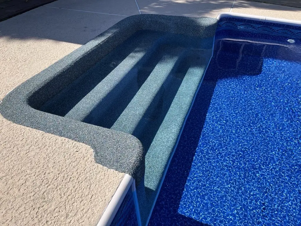 Gray Rebound-coated steps and bench in a pool with a blue patterned liner