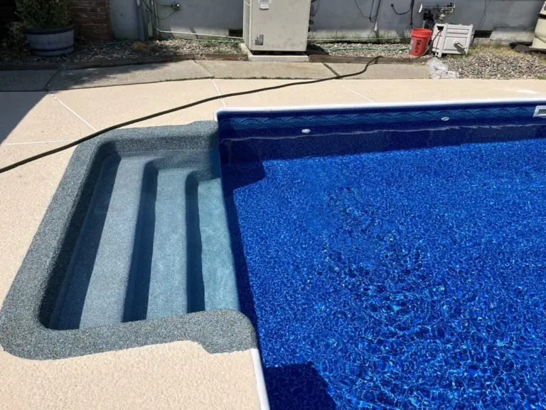 Rebound-coated steps across a corner of a pool with a deep blue liner