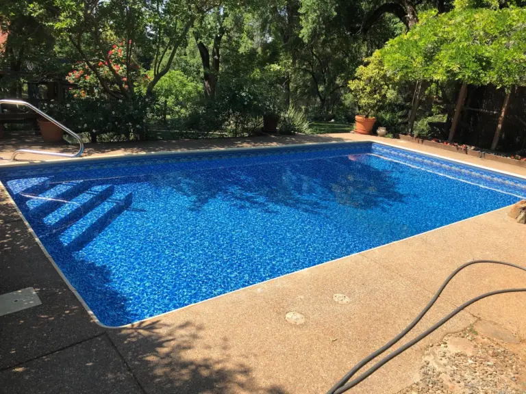 Rectangular pool with vinyl-covered steps across the shallow end and a handrail