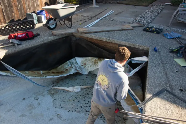 A crew member cutting out the old liner at the shallow end