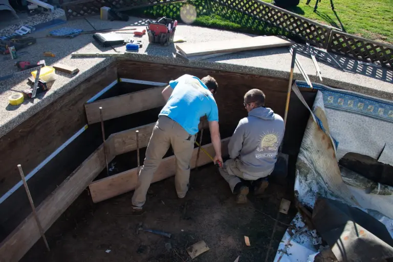 Two crew members setting wood forms for the steps inside the pool