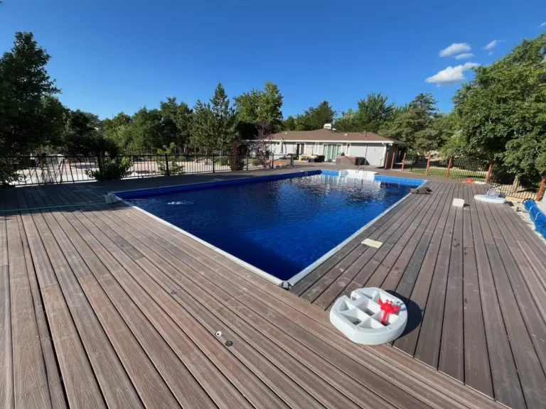 Pool with a deep blue liner surrounded by a wood deck, a pool float resting on the boards